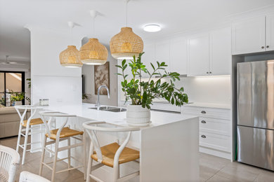 This is an example of a mid-sized contemporary galley eat-in kitchen in Gold Coast - Tweed with an undermount sink, shaker cabinets, white cabinets, quartz benchtops, white splashback, engineered quartz splashback, stainless steel appliances, ceramic floors, with island, beige floor and white benchtop.