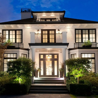 Klassisk inredning av ett mellanstort vitt hus, med tre eller fler plan, tegel och valmat tak