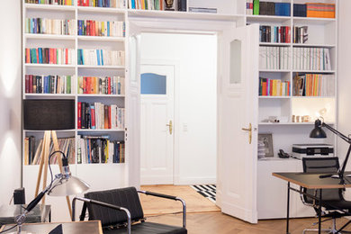 Geräumiges Modernes Lesezimmer mit weißer Wandfarbe, braunem Holzboden, freistehendem Schreibtisch und beigem Boden in Berlin