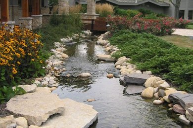 This is an example of a contemporary front yard garden in Milwaukee with a water feature and natural stone pavers.