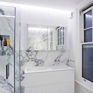 Design ideas for a medium sized modern shower room in London with flat-panel cabinets, white cabinets, a corner shower, a wall mounted toilet, white tiles, white walls, marble flooring, a console sink and solid surface worktops.