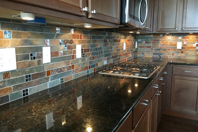 Inspiration for a rustic dark wood floor and brown floor kitchen remodel in Denver with recessed-panel cabinets, dark wood cabinets, granite countertops, multicolored backsplash, slate backsplash and stainless steel appliances