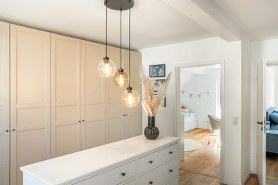 Geräumiges, Neutrales Modernes Ankleidezimmer mit beigen Schränken, hellem Holzboden und braunem Boden in Köln