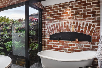 This is an example of an industrial bathroom in Perth with a claw-foot tub, engineered quartz benchtops, white benchtops and black floor.
