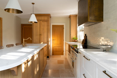 Inspiration for a classic l-shaped kitchen in Cheshire with a single-bowl sink, shaker cabinets, light wood cabinets, quartz worktops, white splashback, porcelain splashback, integrated appliances, limestone flooring, an island, beige floors and white worktops.