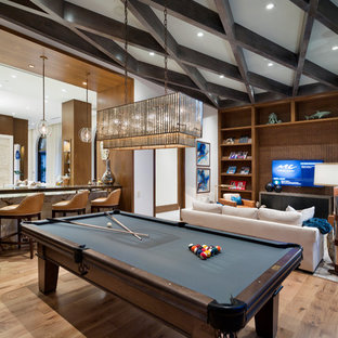 Immagine di un soggiorno mediterraneo aperto con pareti bianche, pavimento in legno massello medio, pavimento marrone e sala giochi