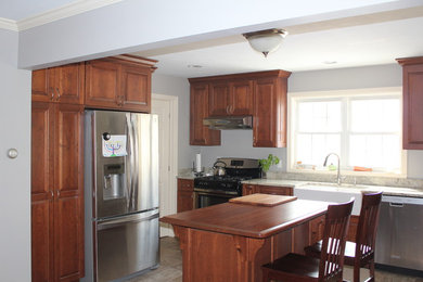 Mid-sized elegant single-wall ceramic tile eat-in kitchen photo in Other with a farmhouse sink, raised-panel cabinets, medium tone wood cabinets, granite countertops, stainless steel appliances and an island