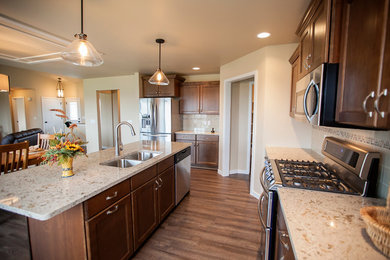 Eat-in kitchen - large craftsman u-shaped vinyl floor eat-in kitchen idea in Milwaukee with an integrated sink, medium tone wood cabinets, quartz countertops, beige backsplash, glass tile backsplash, stainless steel appliances, an island and shaker cabinets