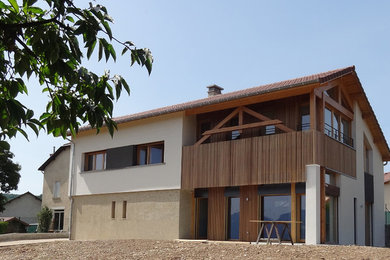 Cette photo montre une grande façade de maison beige tendance à un étage avec un revêtement mixte et un toit à deux pans.