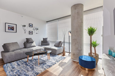 Mid-sized minimalist formal and loft-style medium tone wood floor, brown floor and exposed beam living room photo in Chicago with white walls, no fireplace and a wall-mounted tv