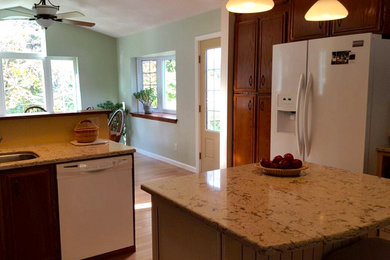 Eat-in kitchen - mid-sized traditional light wood floor eat-in kitchen idea in New York with medium tone wood cabinets, granite countertops, black backsplash, white appliances, an island, an undermount sink and recessed-panel cabinets