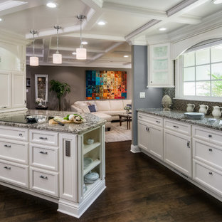 Новый формат декора квартиры: п-образная, отдельная кухня среднего размера в классическом стиле с фасадами с утопленной филенкой, белыми фасадами, разноцветным фартуком, фартуком из плитки мозаики, техникой из нержавеющей стали, темным паркетным полом, полуостровом, столешницей из гранита и коричневым полом