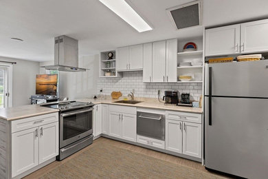 Inspiration for a mid-sized timeless l-shaped laminate floor and gray floor eat-in kitchen remodel in Boston with a drop-in sink, shaker cabinets, white cabinets, laminate countertops, white backsplash, ceramic backsplash, stainless steel appliances, an island and gray countertops