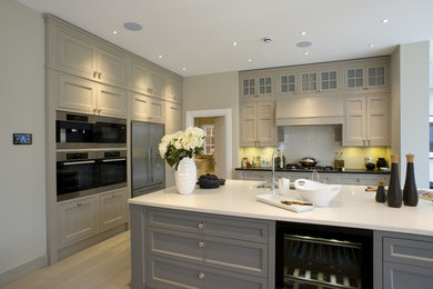 Transitional kitchen in London with an undermount sink, recessed-panel cabinets, grey cabinets, white splashback and stainless steel appliances.