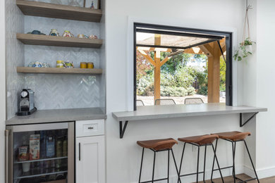 This is an example of a medium sized rural single-wall home bar in Orange County with floating shelves, beige cabinets, quartz worktops, marble splashback, medium hardwood flooring and grey worktops.