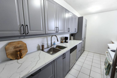 Example of a mid-sized 1950s galley porcelain tile and white floor enclosed kitchen design in Toronto with a double-bowl sink, louvered cabinets, gray cabinets, quartz countertops, white backsplash, quartz backsplash, stainless steel appliances, no island and white countertops