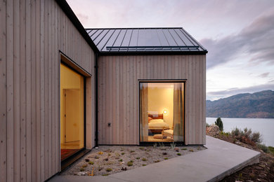 Modelo de fachada de casa gris y negra nórdica de tamaño medio de una planta con revestimiento de madera, tejado a dos aguas, tejado de metal y panel y listón