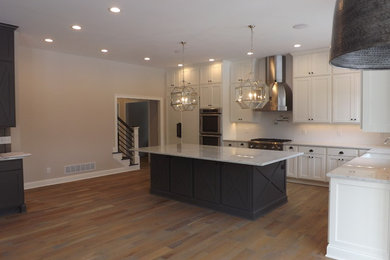 Example of a farmhouse light wood floor kitchen design in Columbus with a farmhouse sink, shaker cabinets, white cabinets, marble countertops, white backsplash, ceramic backsplash, paneled appliances and an island