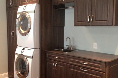 Example of a transitional laundry room design in Atlanta with an integrated sink, flat-panel cabinets and a stacked washer/dryer