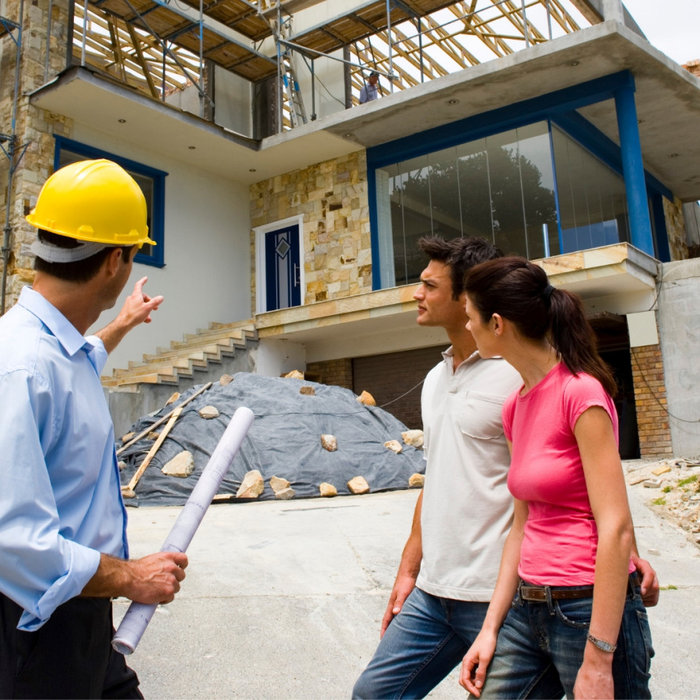 A contractor discussing remodeling plans with a couple in front of a house under construction, symbolizing a stress-free renovation process.