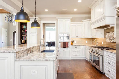 Example of a mid-sized transitional l-shaped medium tone wood floor and brown floor open concept kitchen design in Other with an undermount sink, beaded inset cabinets, white cabinets, granite countertops, gray backsplash, subway tile backsplash, stainless steel appliances, an island and multicolored countertops
