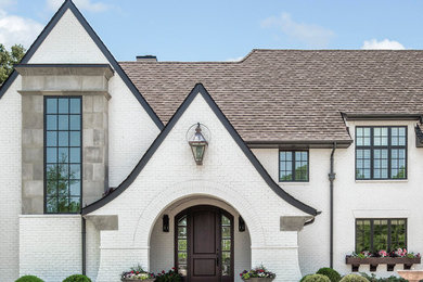 Large country white three-story brick house exterior idea in Charlotte with a shingle roof