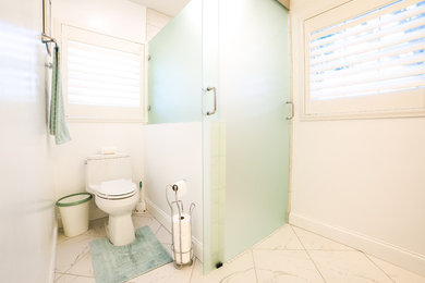 Example of a mid-sized minimalist master white tile and porcelain tile porcelain tile and white floor sliding shower door design in Tampa with a one-piece toilet, white walls, an undermount sink and quartz countertops
