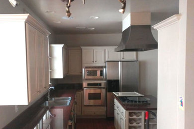 Enclosed kitchen - mid-sized transitional l-shaped dark wood floor and brown floor enclosed kitchen idea in Charlotte with a double-bowl sink, shaker cabinets, white cabinets, granite countertops, stainless steel appliances and an island