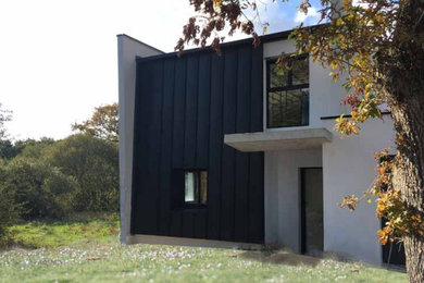 Idées déco pour une façade de maison métallique et noire contemporaine de taille moyenne et à un étage avec un toit plat et un toit en métal.