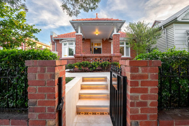 Small victorian front yard full sun garden with a garden path, natural stone pavers and a metal fence for spring.