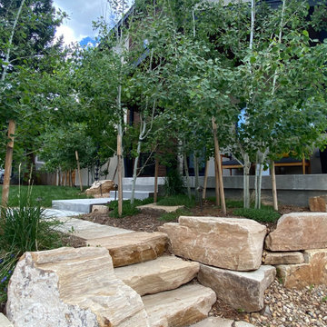 Mountain inspired minimalist boulder retaining walls and plantings.