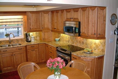 Exempel på ett mellanstort medelhavsstil kök, med en undermonterad diskho, luckor med upphöjd panel, skåp i mellenmörkt trä, granitbänkskiva, beige stänkskydd, stänkskydd i porslinskakel, rostfria vitvaror och ljust trägolv