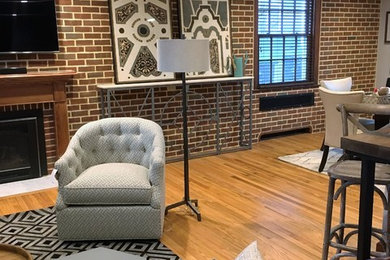 Example of a mid-sized transitional formal and open concept light wood floor and beige floor living room design in Other with beige walls, a standard fireplace, a brick fireplace and a wall-mounted tv