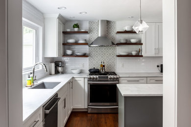 Mid-sized minimalist l-shaped medium tone wood floor and brown floor enclosed kitchen photo in Philadelphia with an undermount sink, recessed-panel cabinets, white cabinets, white backsplash, subway tile backsplash, stainless steel appliances, an island and white countertops