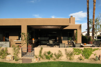 This is an example of a mid-sized contemporary one-storey stucco beige house exterior in Other with a flat roof.