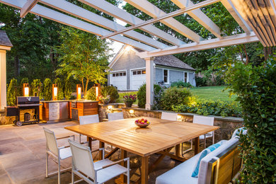 Example of a mid-sized classic backyard stone patio design in New York with a pergola and a bbq area