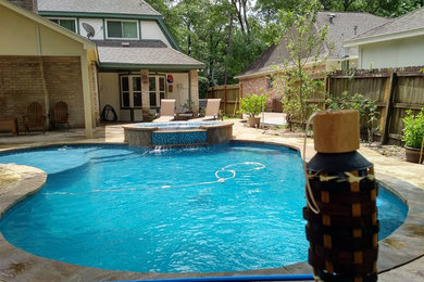 Design ideas for a small traditional backyard custom-shaped natural pool in Houston with a hot tub and stamped concrete.