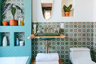 This is an example of a mediterranean bathroom in San Francisco with a shower/bathtub combo, green tile, ceramic tile, white walls, ceramic floors, a pedestal sink, wood benchtops, green floor and an open shower.