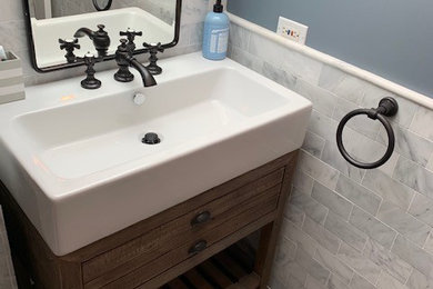 Bathroom - small contemporary porcelain tile and gray floor bathroom idea in Chicago with recessed-panel cabinets, distressed cabinets, a one-piece toilet, blue walls, an integrated sink, solid surface countertops and a hinged shower door