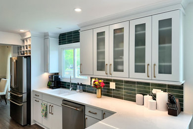 Inspiration for a mid-sized transitional eat-in kitchen remodel in Chicago with flat-panel cabinets, white cabinets, green backsplash, ceramic backsplash, stainless steel appliances, a peninsula and white countertops