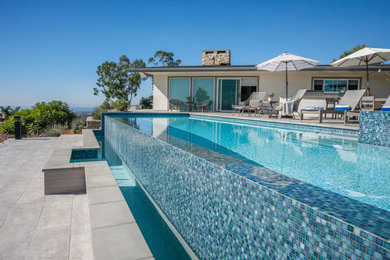 Example of a large minimalist backyard concrete paver and rectangular infinity pool design in Los Angeles