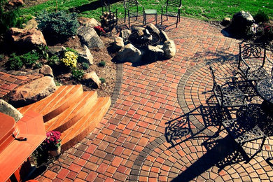 Design ideas for a large country backyard patio in Minneapolis with a fire feature, brick pavers and no cover.