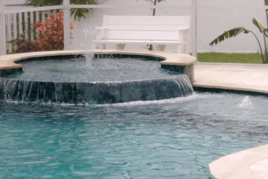Hot tub - mid-sized tropical backyard concrete paver and l-shaped lap hot tub idea in Other