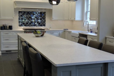 Inspiration for a large transitional u-shaped kitchen in DC Metro with a farmhouse sink, flat-panel cabinets, white cabinets, quartz benchtops, blue splashback, ceramic splashback, stainless steel appliances, porcelain floors, with island, grey floor and white benchtop.