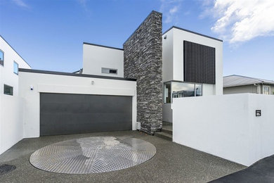 Inspiration for a mid-sized modern two-storey white townhouse exterior in Christchurch with mixed siding, a shed roof and a metal roof.