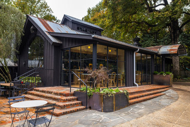 Mid-sized farmhouse black two-story painted brick and board and batten gable roof photo in Atlanta with a metal roof and a gray roof