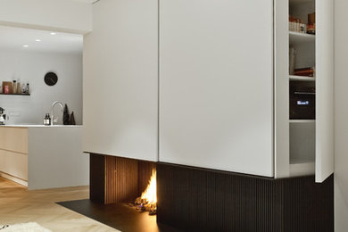 Geräumiges, Offenes Modernes Wohnzimmer mit weißer Wandfarbe, Kamin, Kaminumrandung aus Stein und verstecktem TV in Sonstige