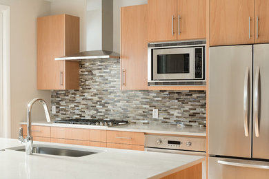 Inspiration for a large modern light wood floor kitchen remodel in Denver with an undermount sink, flat-panel cabinets, light wood cabinets, quartz countertops, multicolored backsplash, glass tile backsplash, stainless steel appliances and an island