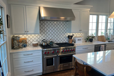 シャーロットにある高級な広いトラディショナルスタイルのおしゃれなキッチン (アンダーカウンターシンク、フラットパネル扉のキャビネット、白いキャビネット、クオーツストーンカウンター、白いキッチンパネル、大理石のキッチンパネル、パネルと同色の調理設備、濃色無垢フローリング、茶色い床、白いキッチンカウンター) の写真