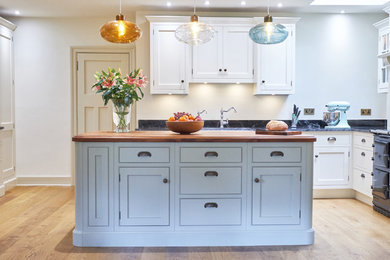 Inspiration for a large transitional u-shaped eat-in kitchen in Edinburgh with shaker cabinets, white cabinets, granite benchtops, light hardwood floors, with island and beige floor.